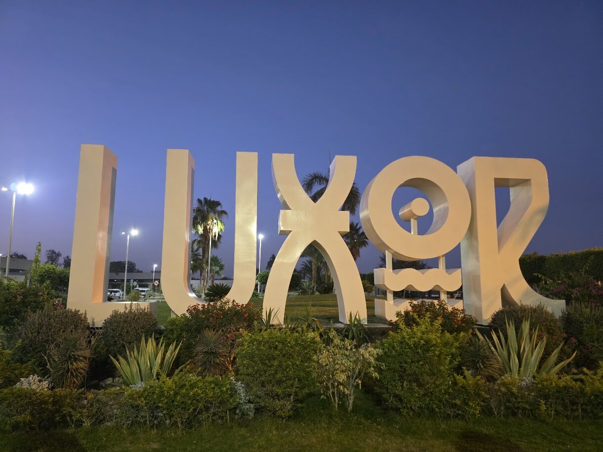 Large LUXOR sign in a park at dusk